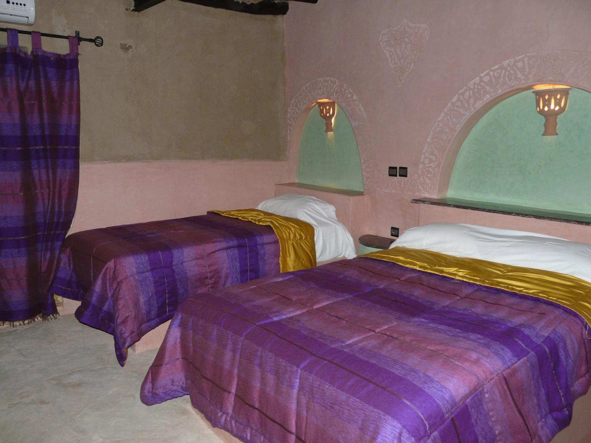 Chambre avec deux lits et textiles violets