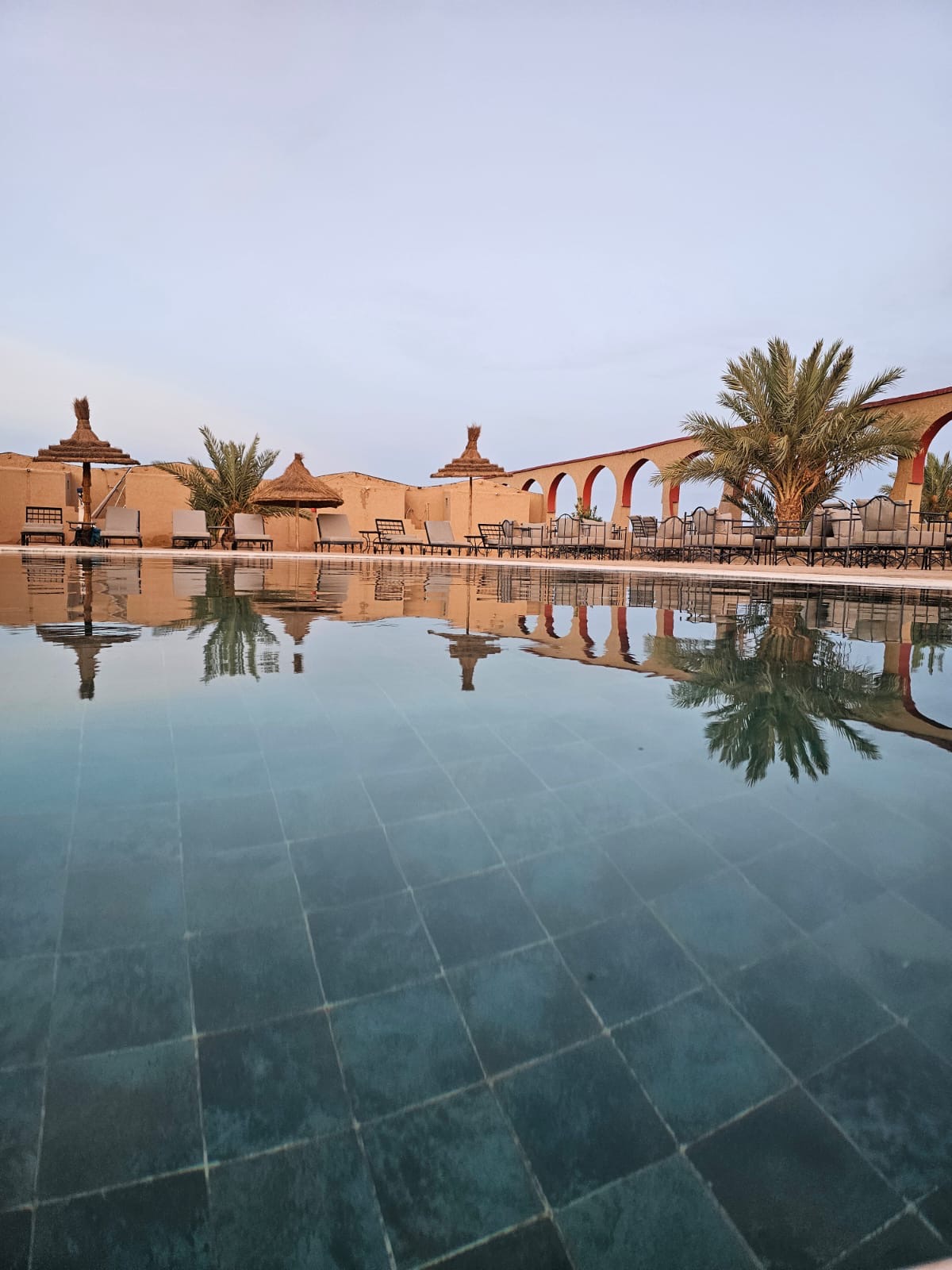 Piscine miroir avec arches et palmiers